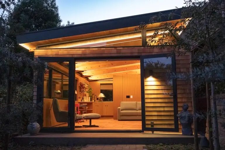 Modern backyard ADU construction with warm interior lighting and large glass doors