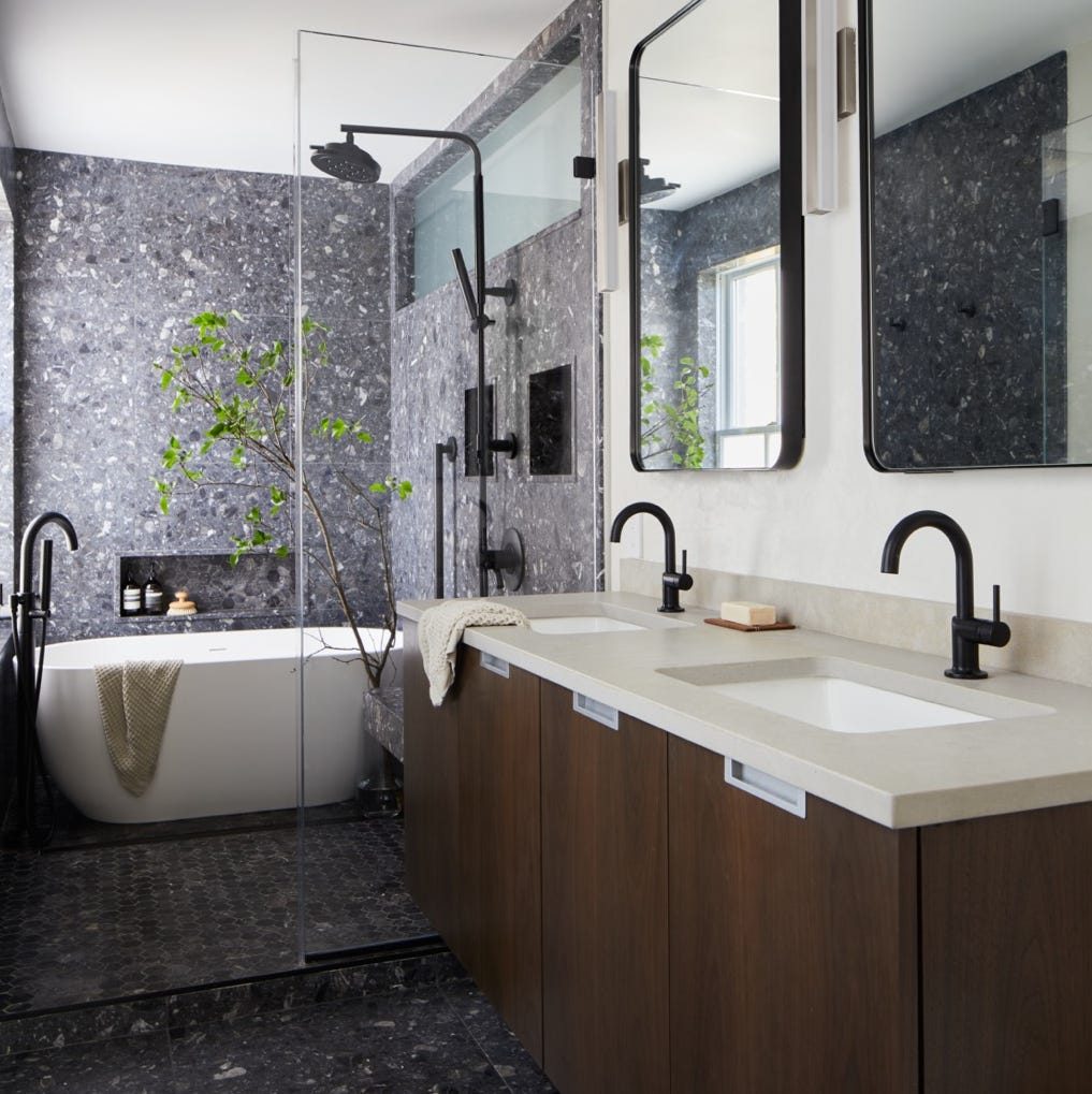 Contemporary bathroom remodel with dark stone walls and freestanding tub