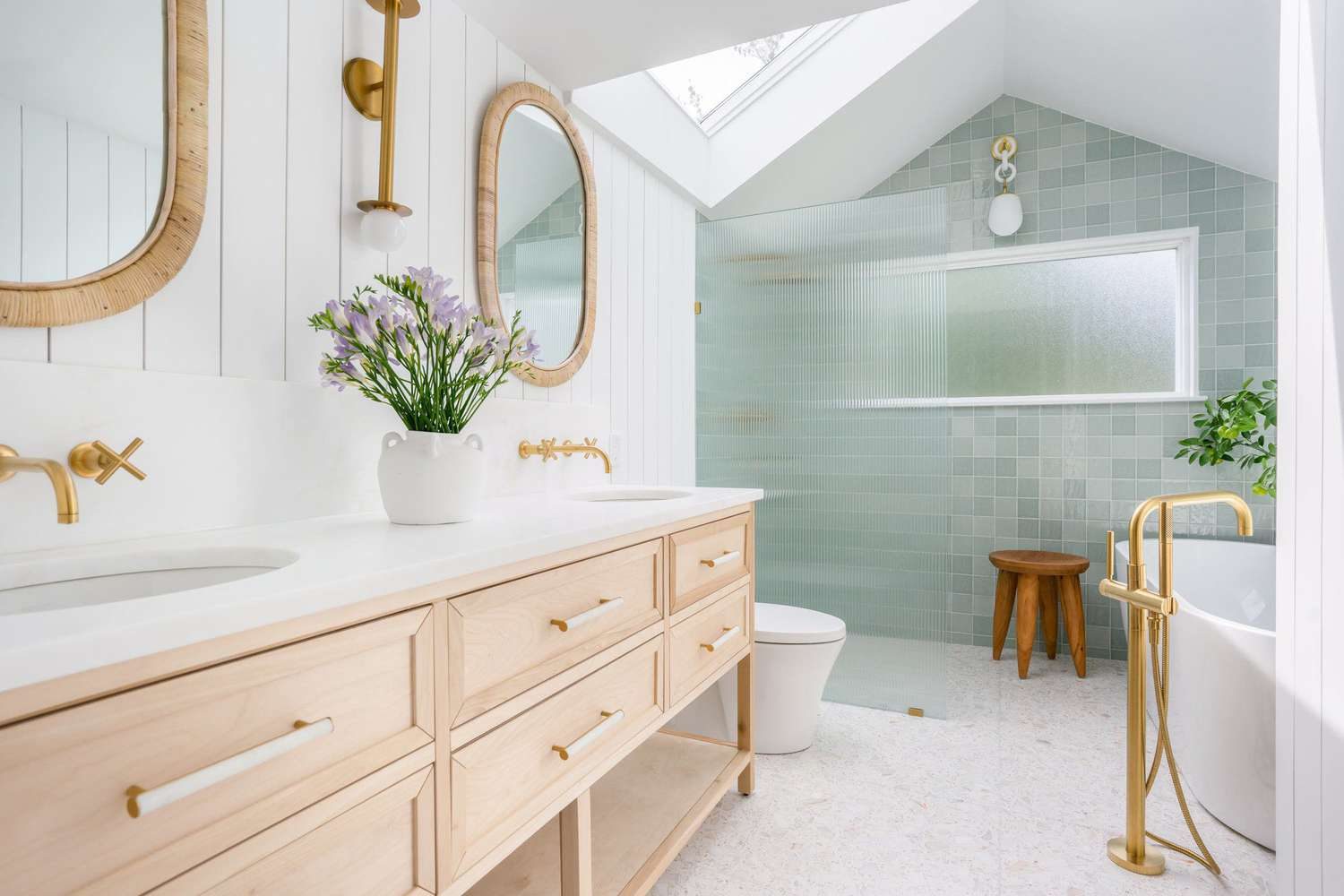 Bright bathroom renovation featuring a freestanding tub and light wood vanity
