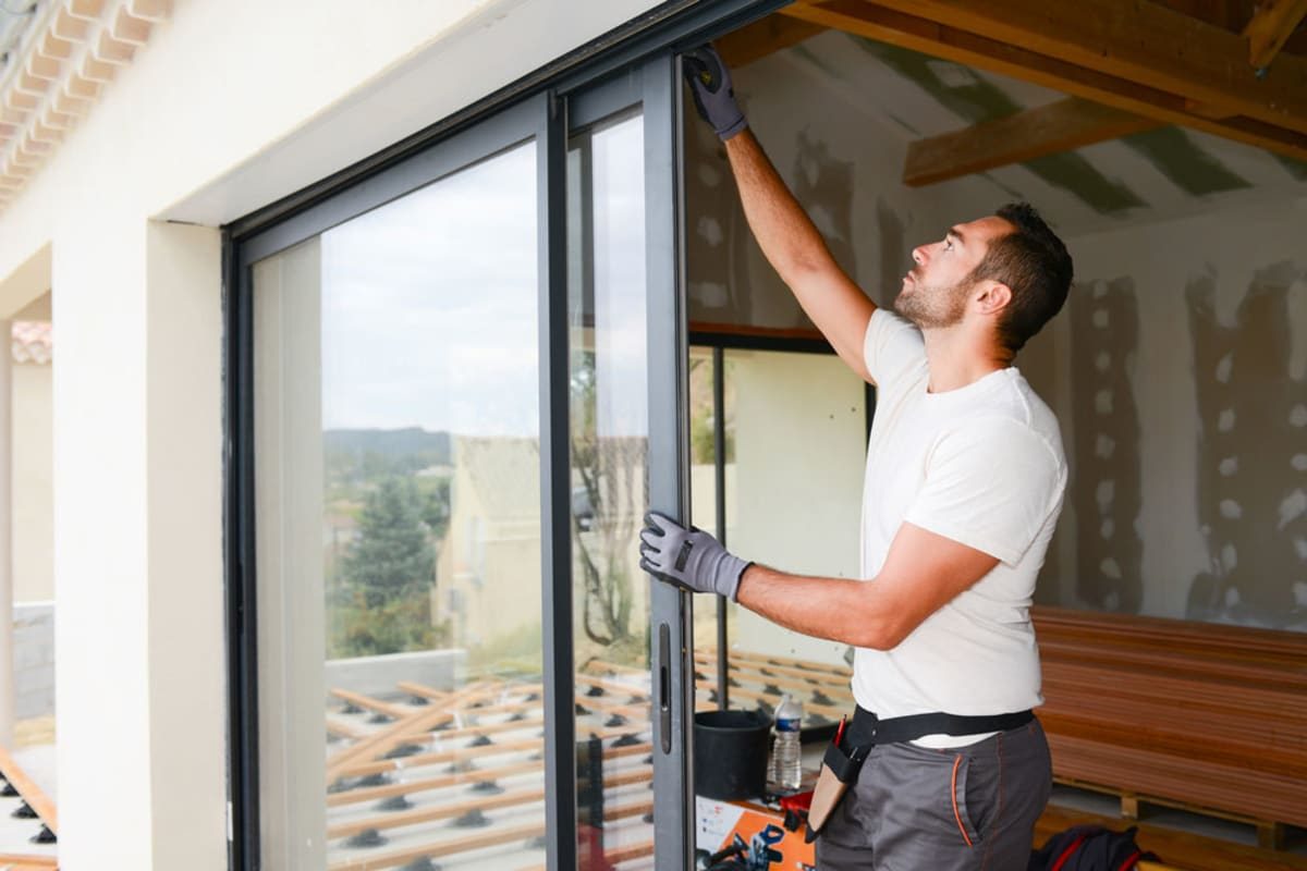 Professional installers fitting a large sliding patio door in a modern home