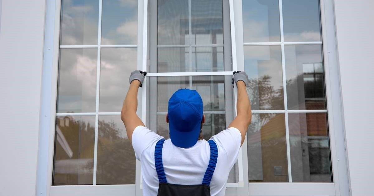 Worker carefully positioning a replacement window into an existing wall opening