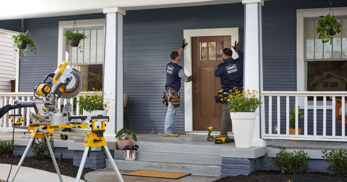 Contractors securing a new front entry door during a home remodeling project