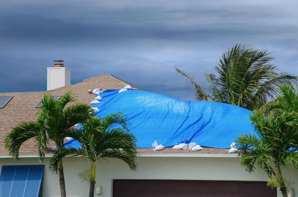 Emergency roof tarping service securing a damaged roof with a large blue tarp
