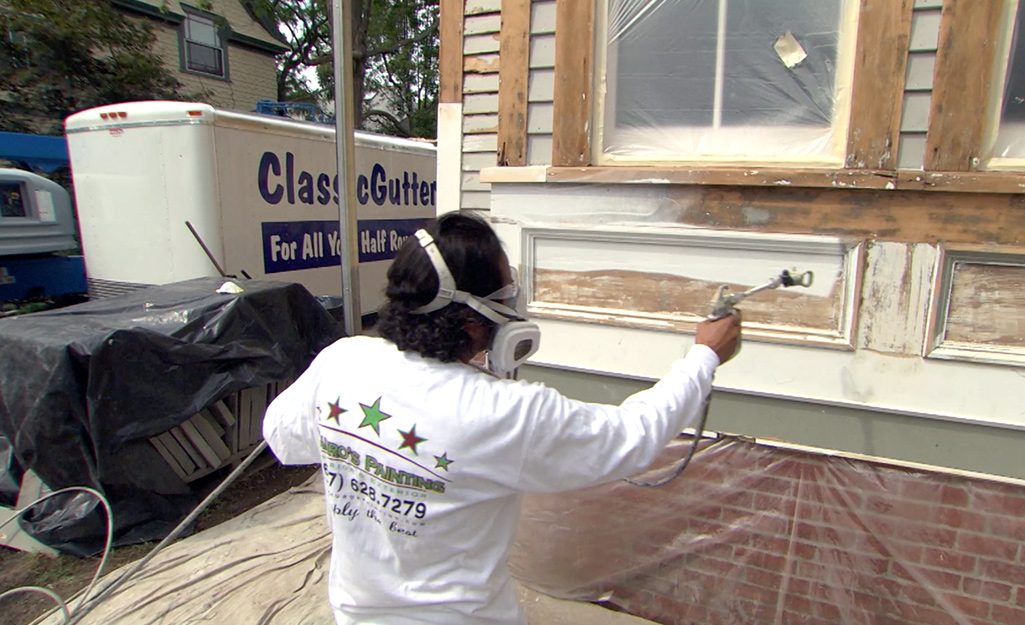 Professional painter using a spray gun to paint a home exterior