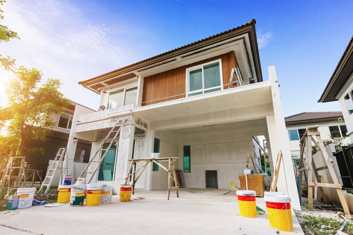 Professional painters working on the exterior of a large residential home