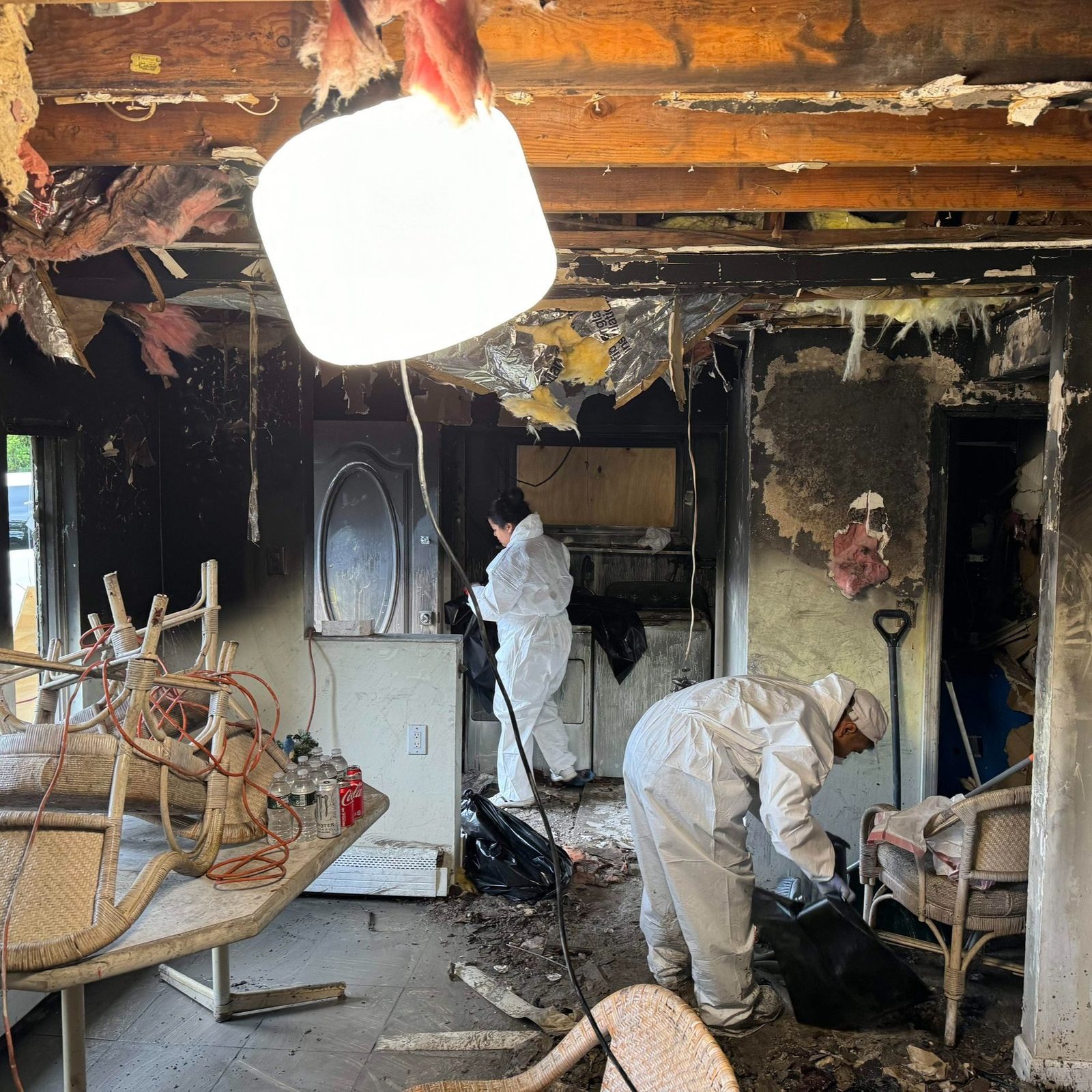 Professional smoke damage cleanup crew working inside a severely fire-damaged home interior