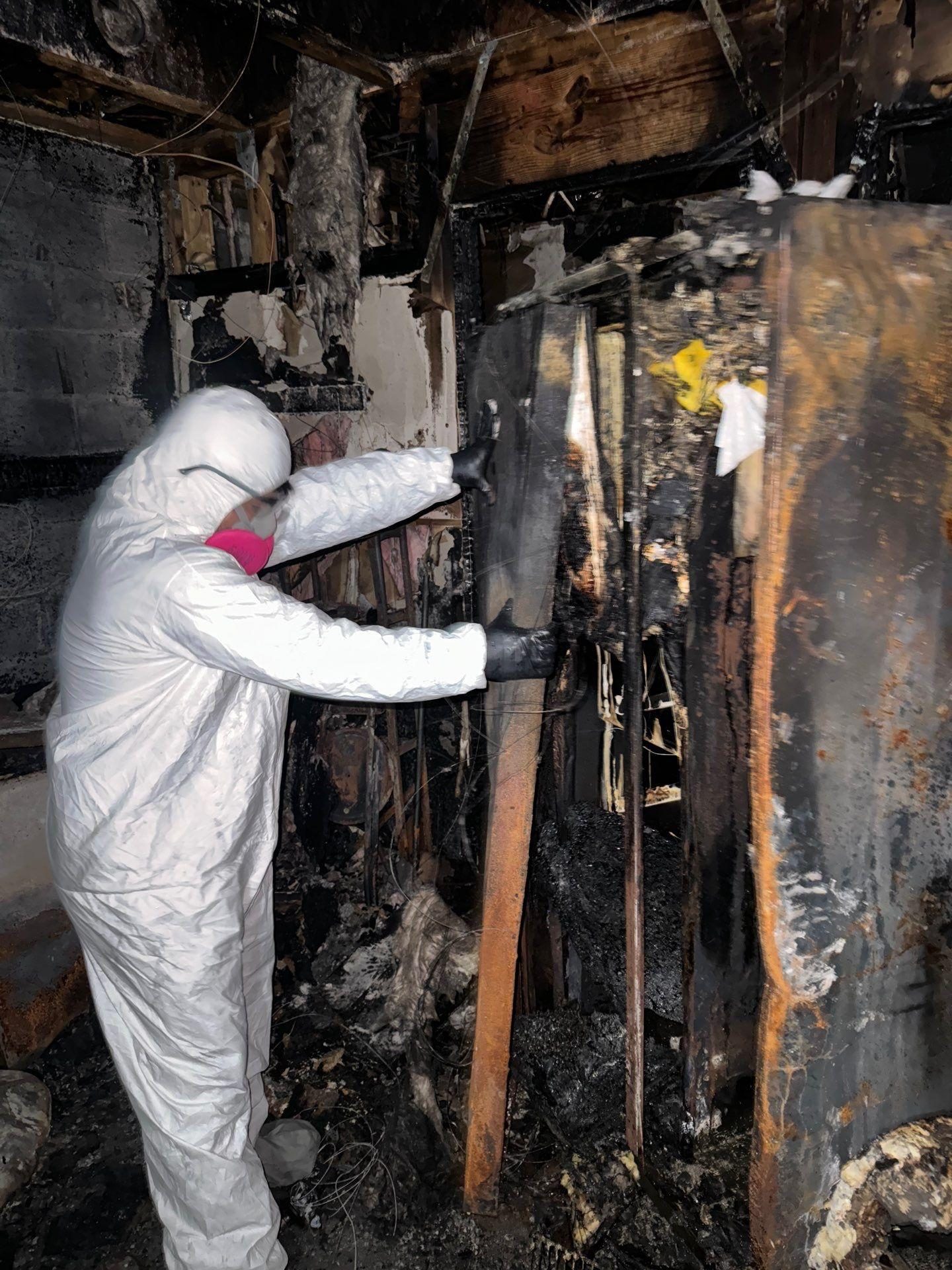 Technician in full protective suit performing smoke damage cleanup in a commercial building