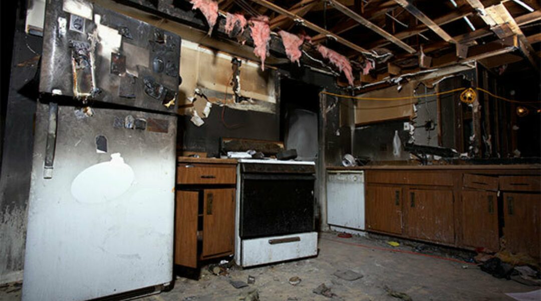 Smoke damage cleanup crew working on restoring a fire-damaged kitchen interior