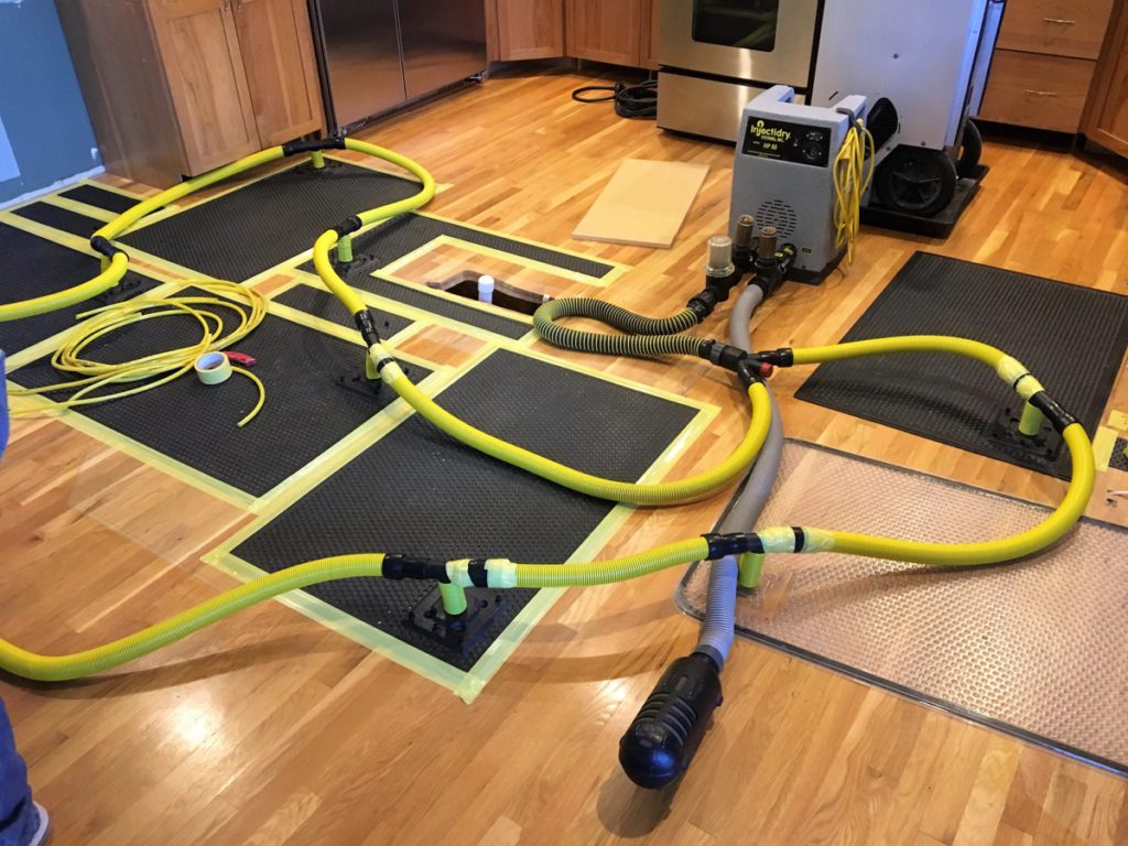 Drying equipment and dehumidifiers set up on a wood floor for water damage restoration