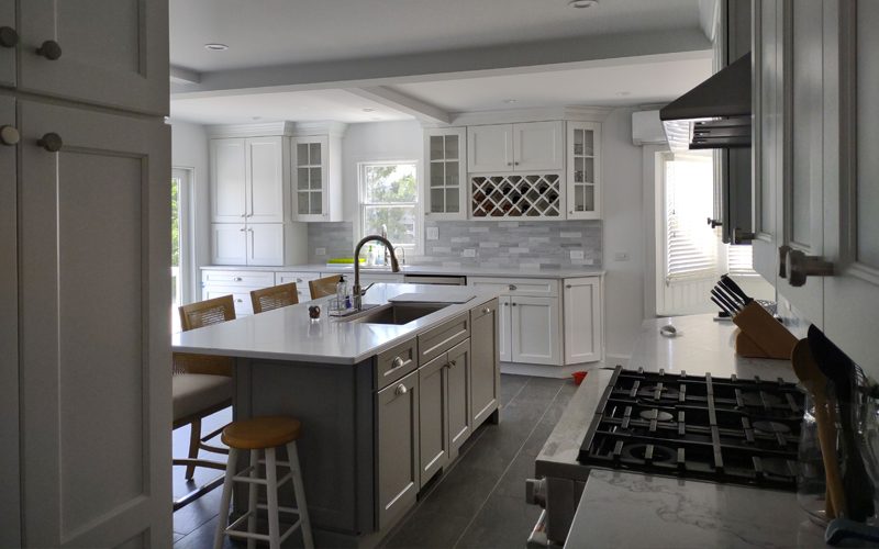 Modern kitchen renovation featuring gray cabinetry and a central island with seating