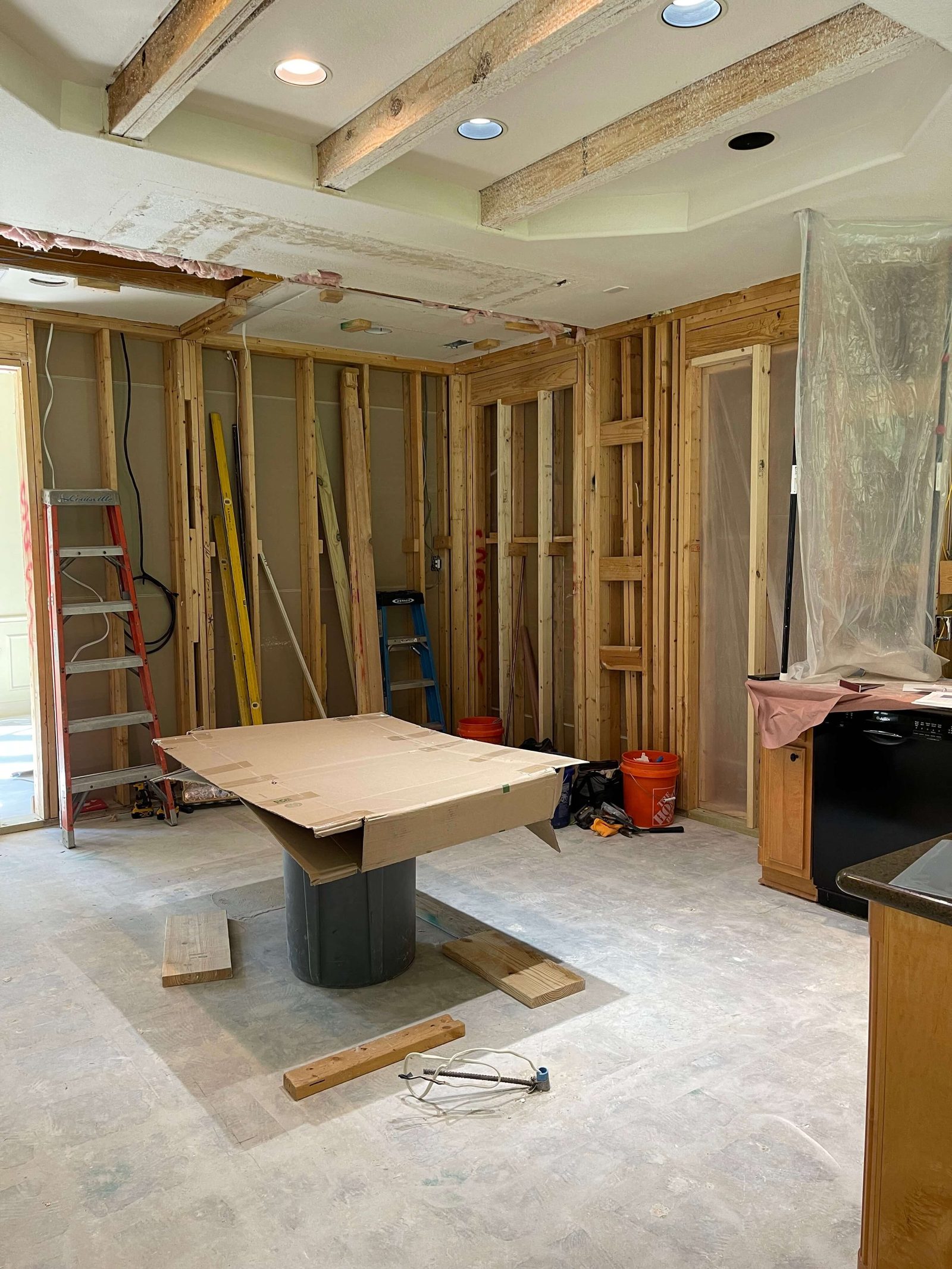 Kitchen remodeling in progress with exposed framing and contractor tools