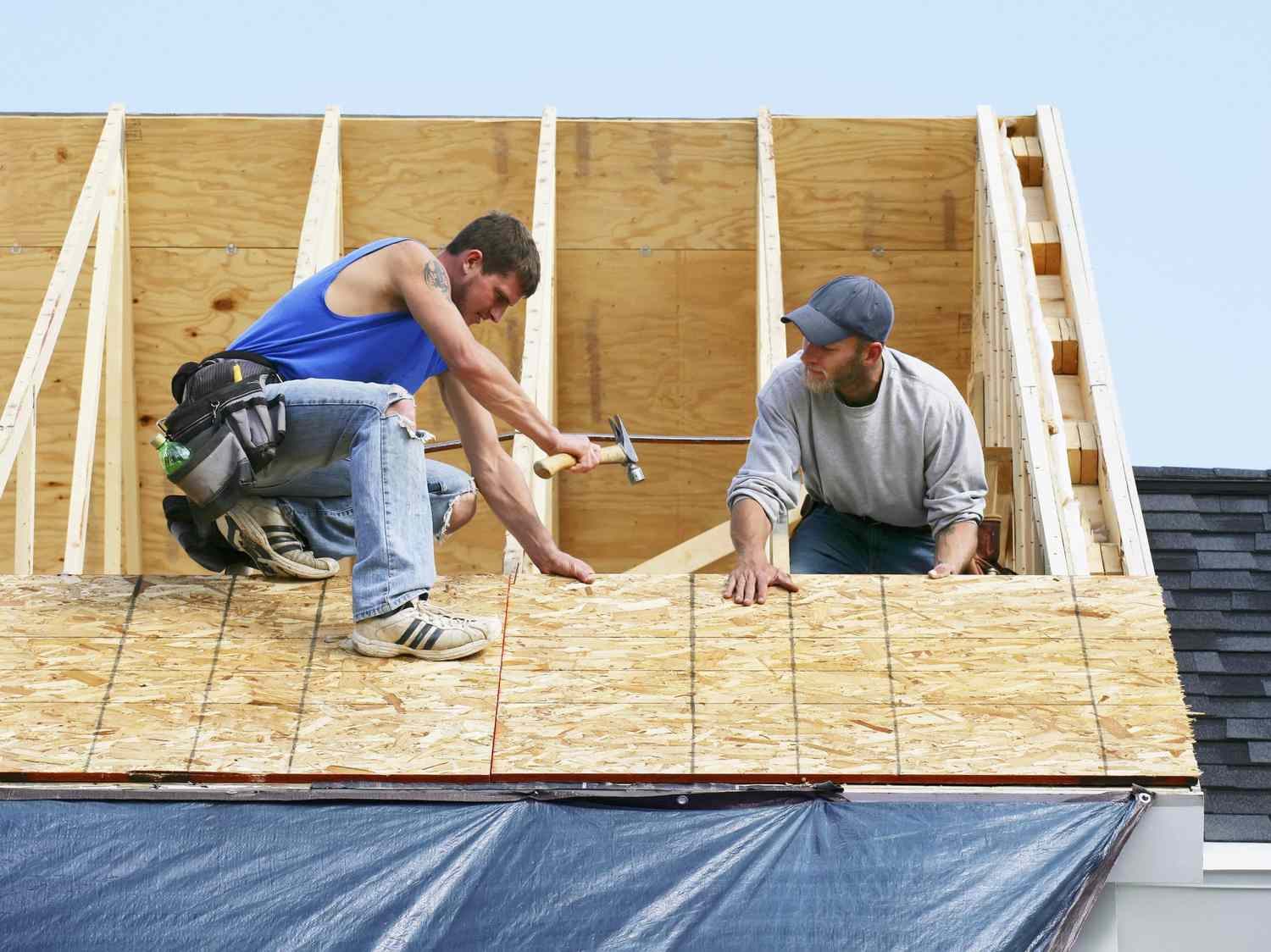 Professional roofers installing new plywood decking during a residential roof replacement